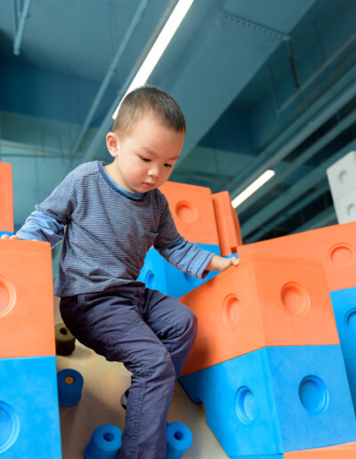Un enfant explore un jeu de construction géant dans la plaine de jeux couverte