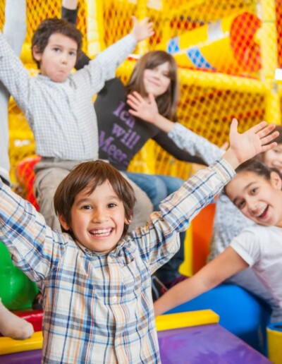 Des enfants souriants qui lèvent les bras dans la plaine de jeux couverte