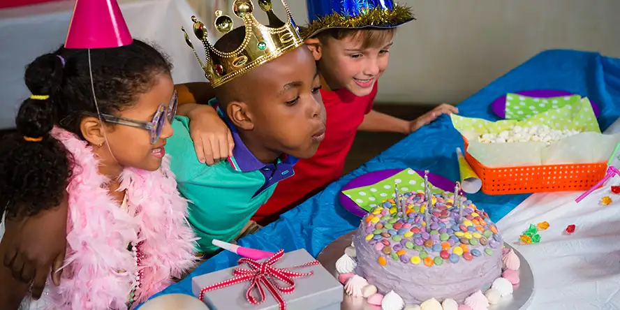 Un enfant très souriant qui fête son anniversaire avec un très beau gâteau au chocolat dans la plaine de jeu couverte