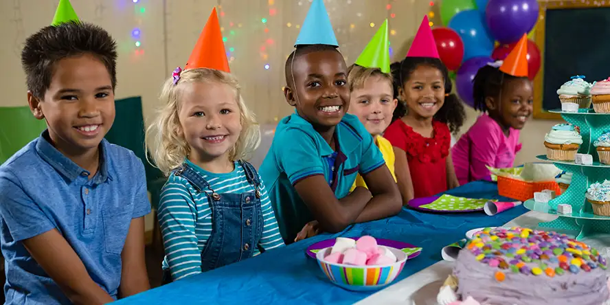 Un enfant très souriant qui fête son anniversaire avec un très beau gâteau au chocolat dans la plaine de jeu couverte
