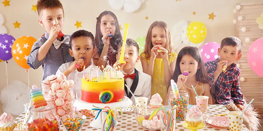 Un enfant très souriant qui fête son anniversaire avec un très beau gâteau au chocolat dans la plaine de jeu couverte